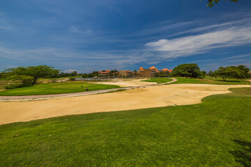 Naklejka premium Beautiful view of golf course on island of Aruba, set against backdrop of tropical vegetation and hotel.