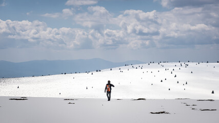 Beautiful snow covered mountain highlands and a mountain hiker with orange backpack - 683864607