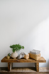 Wicker basket with folded, fresh shower towel and vase with green branch in bathroom