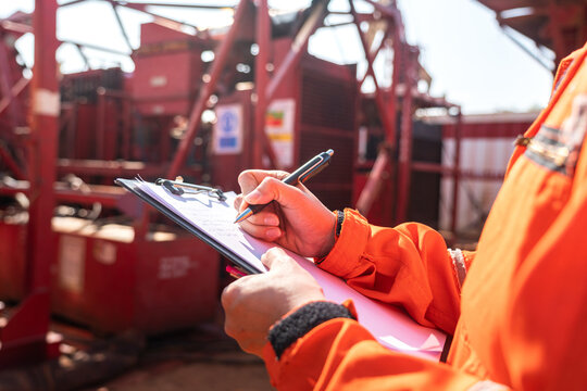 Maintenance engineer performs audit and inspection the power generator machine (as background) at the oil refinery plant working site. Industrial safety working wit people action, selective focus.