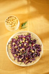 red cabbage and corn salad on a ceramic plate, yellow background, daylight, no people