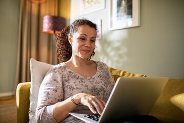 Woman on couch working on laptop from home