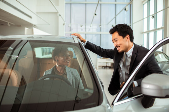Salesperson Showing a New Car to a Potential Buyer at Dealership
