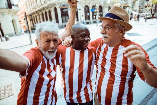 Joyful Senior Friends Celebrating in Sports Jerseys on a Sunny Day in the City