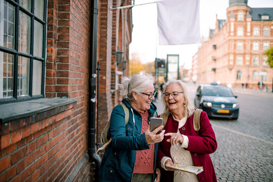 Joyful Senior Ladies Using Smartphone for Navigation on a City Street