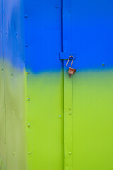 An open steel lock on a colorful metal door