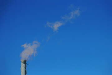 Pipe with white smoke against a blue sky.