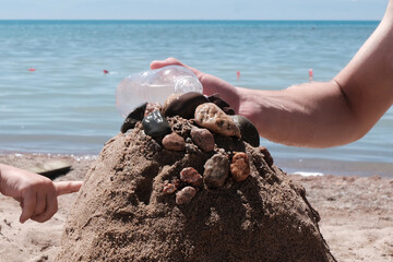 Close-up of a boy's hands building a sand tower. Concept of safe water games, healthy lifestyle, tourism., hand holding a seashell on the beach