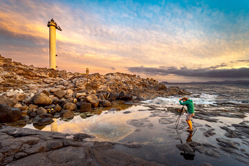 Golden lighthouse captured by photographer at sunset - obrazy, fototapety, plakaty
