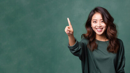 Happy asian woman pointing her finger at copy space for promotion