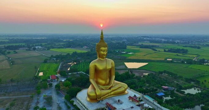 .aerial view The sun was above the head of the biggest golden Buddha at sunset..landmark of Buddhism in Thailand..video 4K Nature video High quality footage for worship and travel concept..