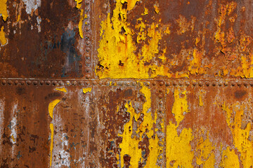 beautifully rusted rivetted sheet metal with leftovers of yellow paint texture and full-frame background