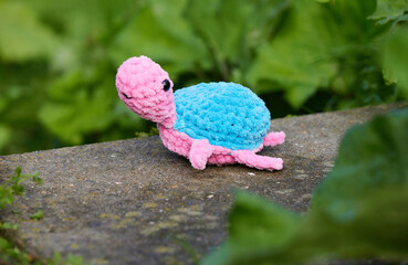 Cute knitted toy turtle in the garden