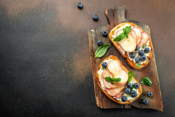 Peach bruschetta with ricotta cheese and blueberries on a wooden board. banner, menu, recipe copy...
