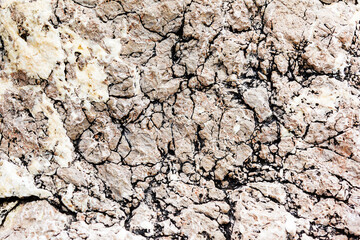 Empty gray stone wall covered with cracks of old house.