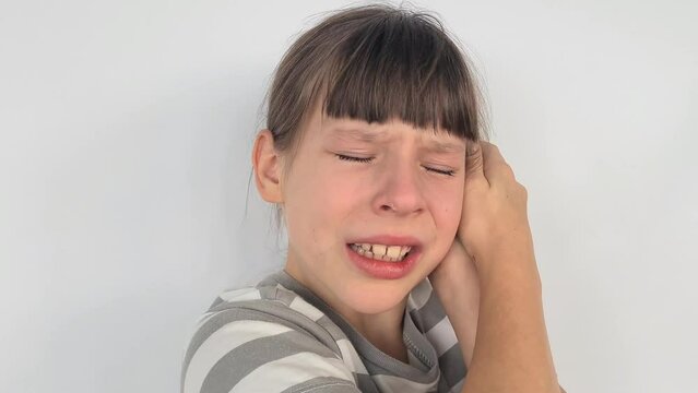 Sad crying teenage girl with headache and severe ear pain. Inflammation of the ear otitis media in children
