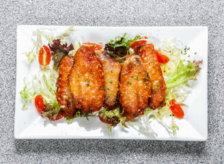 Garlic Honey Chicken Wings with tomato and cabbage salad served in dish isolated on background top view of hong kong food