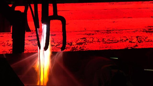Iron foundry. Continuous casting machine. Production of steel billets. Continuous casting machine with blow torch working.  hot steel on conveyor in steel mill. Steel Billets at Torch Cutting
