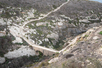 Xlendi, Gozo: View from above of a stone staircase and a path that has been carved into the...