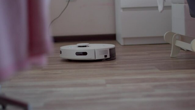 Robot vacuum cleaner that is sitting on the floor next to a chair. Smart Home