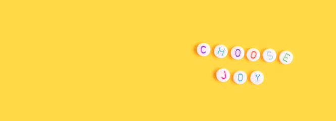 Choose joy. Banner with quote made of beads with letters on a yellow background.