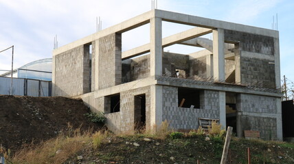 Fototapeta na wymiar box of a two-story cottage under construction without a roof, a block building at the stage of erecting walls, construction of a residential building in a suburban area