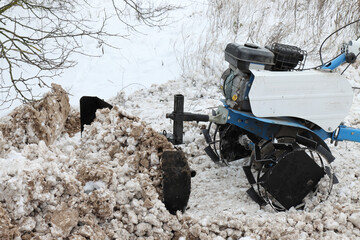 Snow removal using a walk-behind cultivator with a blade - obrazy, fototapety, plakaty