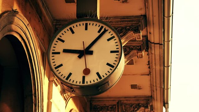 Time machine concept. Clock hands move in opposite direction. Return to past. Wayback machine. Large clock face at station. Antique stucco on old building.  Ljubljana, Slovenia - November 24, 2023