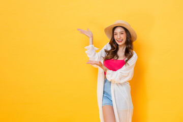 Pretty Asian woman in summer outfit raising hands up to copy space in yellow color isolated background studio shot