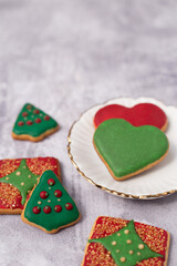 Handmade butter cookies with Christmas decoration in red and green tones on a plate and marble surface