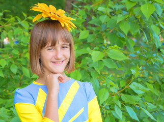 Portrait of a sly mischievous teenage girl with a sunflower on her head