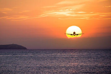 Passenger airplane silhouette agaist a sunset over the ocean
