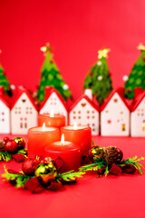 four red burning Advent candles. against the backdrop of Christmas lantern houses. 4 weeks before Christmas, one candle is lit, and on Christmas Day all 4 candles are lit.