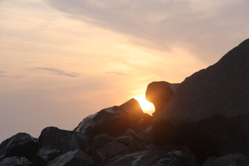 Sun rays at sunset and stones above Black sea coast in the evening, sunset in nature. Batumi,...