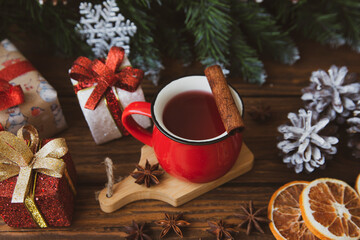 Christmas mood, holiday atmosphere. Red cup of coffee, fir branches with cones, Christmas gifts,...