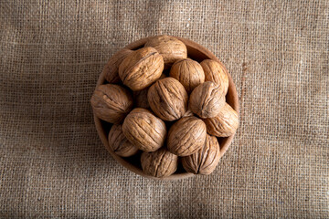 Bowl full of shelled walnuts on burlap sack,top view