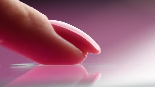 Beautiful nail, manicure Nailpolish, pink shellac UV gel on woman's nail, polish, application varnish, manicure process concept. Perfect healthy oval shape nail, Manicure salon. 