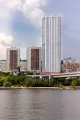 Fototapeta na wymiar skyscraper against the background of a bridge over the river close-up in summer