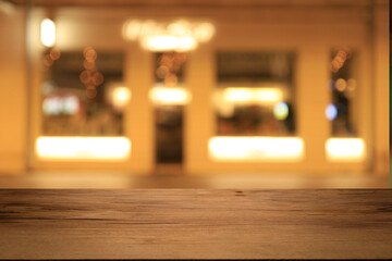 Beautiful empty wood table top counter, window view. Wooden table with blur bokeh background ready for product montage. Abstract blurred bokeh neutral background of city, shop, store, restaurant, city