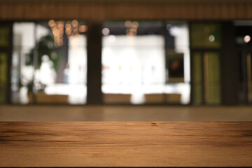 Beautiful empty wood table top counter, window view. Wooden table with blur bokeh background ready for product montage. Abstract blurred bokeh neutral background of city, shop, store, restaurant, city