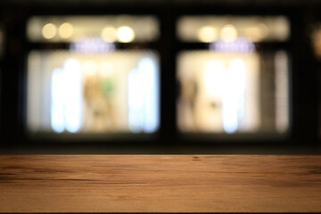 Beautiful empty wood table top counter, window view. Wooden table with blur bokeh background ready for product montage. Abstract blurred bokeh neutral background of city, shop, store, restaurant, city