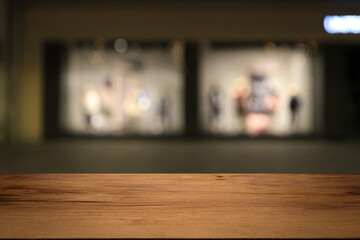 Beautiful empty wood table top counter, window view. Wooden table with blur bokeh background ready for product montage. Abstract blurred bokeh neutral background of city, shop, store, restaurant, city