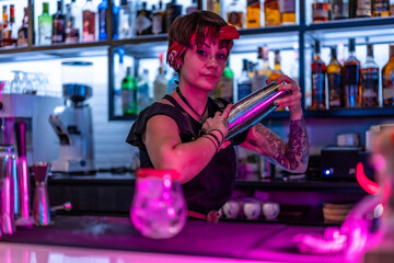 Young female bartender shaking a cocktail in a bar