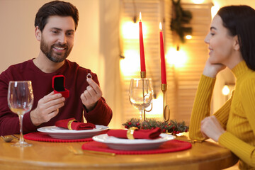 Man with engagement ring making proposal to his girlfriend at home on Christmas, selective focus