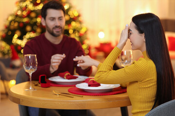 Making proposal. Man putting engagement ring on his girlfriend's finger at home on Christmas, selective focus