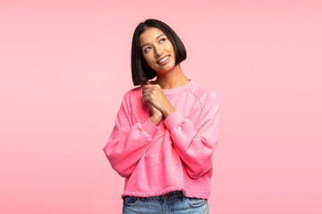 Positive asian woman wearing stylish casual clothes posing, looking away isolated on pink background