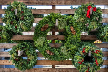 Christmas holiday spirit with fresh wreaths made out of evergreen boughs, pinecones, red berries, and red ribbon
