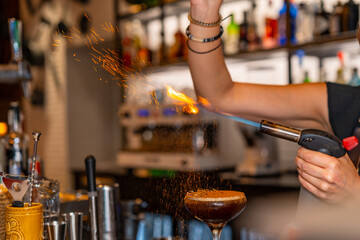 Fototapeta na wymiar Bartender burning the toppings of coffee cocktail in a bar
