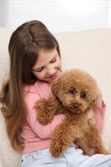 Little child with cute puppy in armchair. Lovely pet