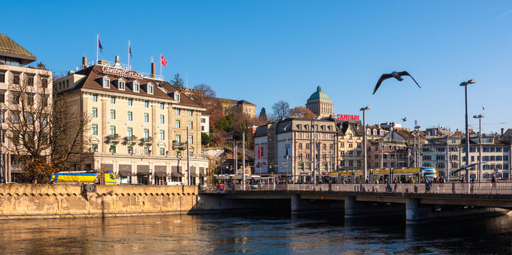 Zurich, Switzerland - November 23, 2023: Anamorphic photo of the river Limmat and cityscape of Zurich with Bahnhof bridge. Central Plaza hotel and Campari publicity.